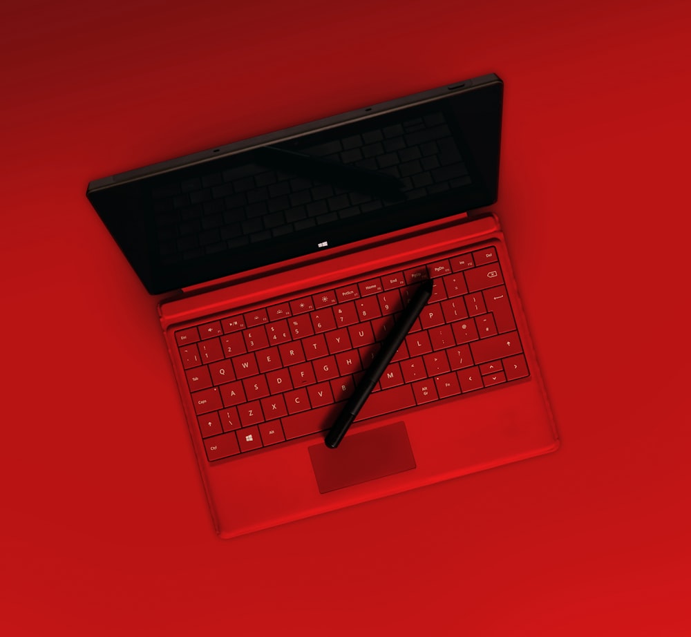 赤いラップトップコンピュータに黒いペン