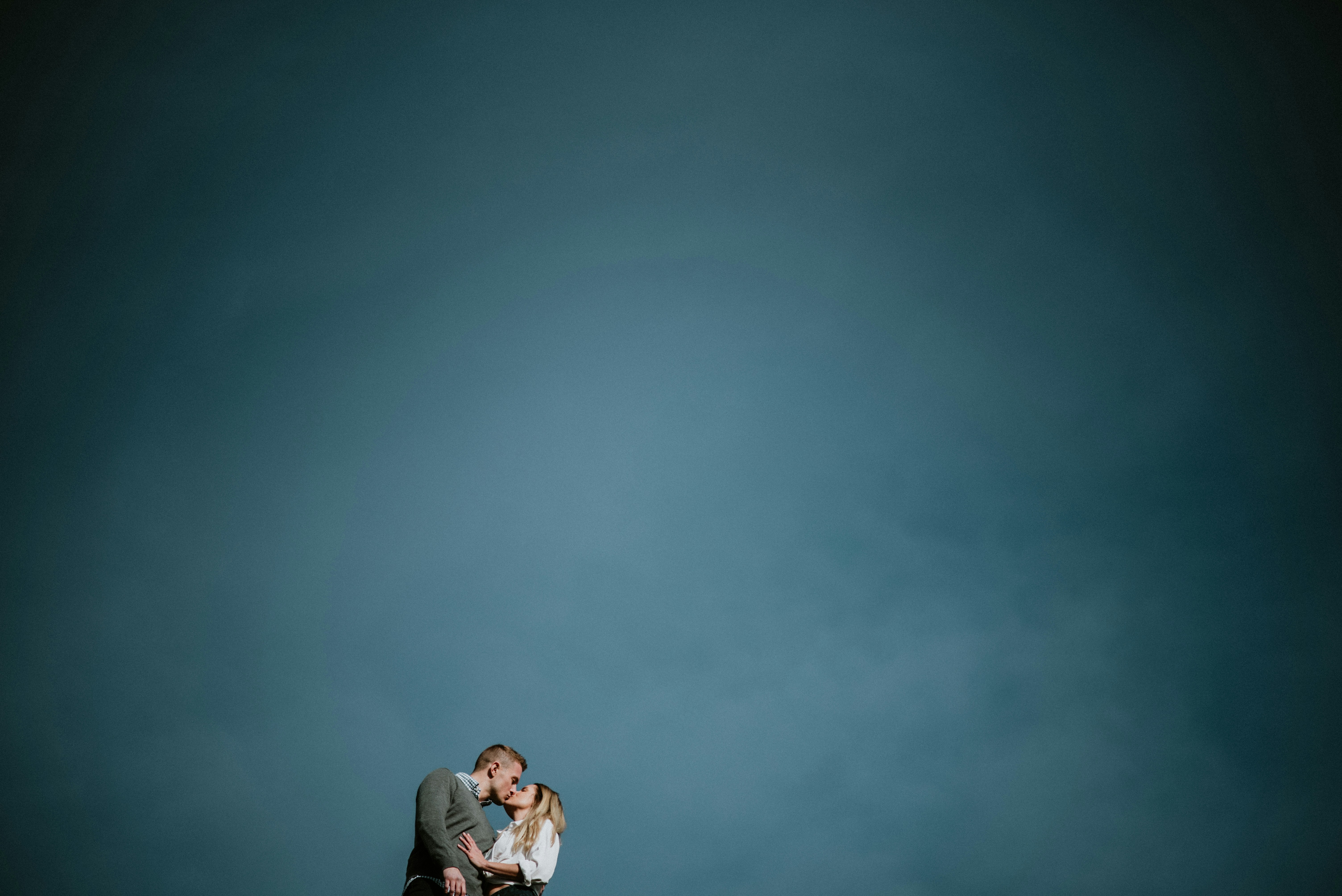 low angle photography of couple kissing under blue sky