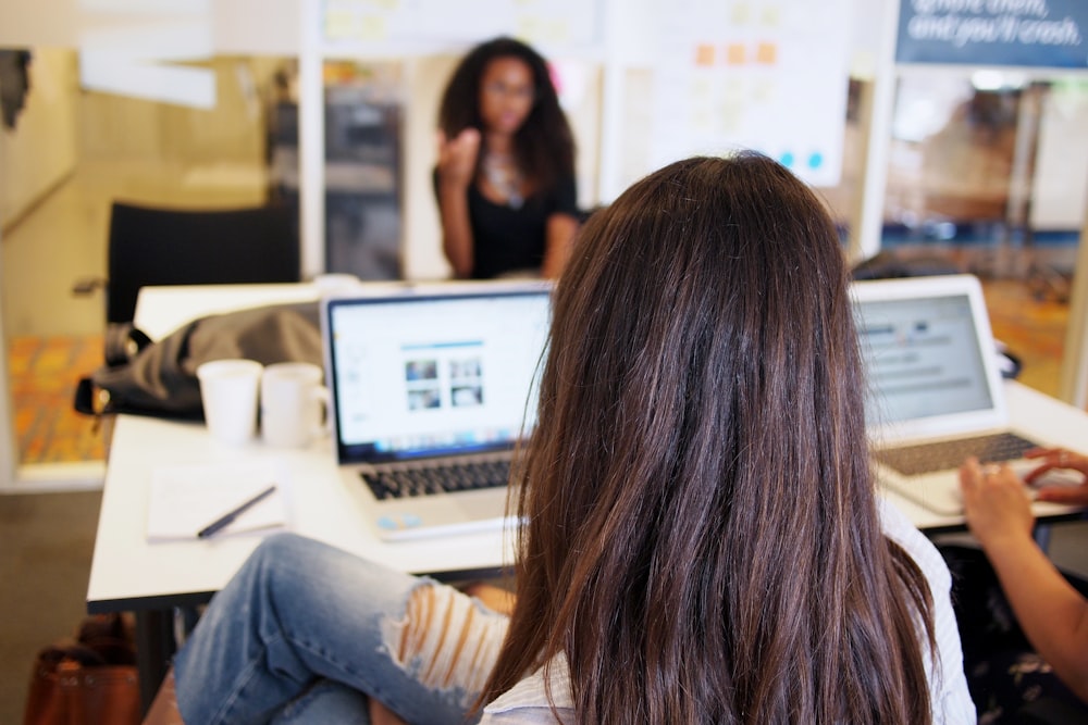 woman sitting while looking at turned on laptop on tabletop