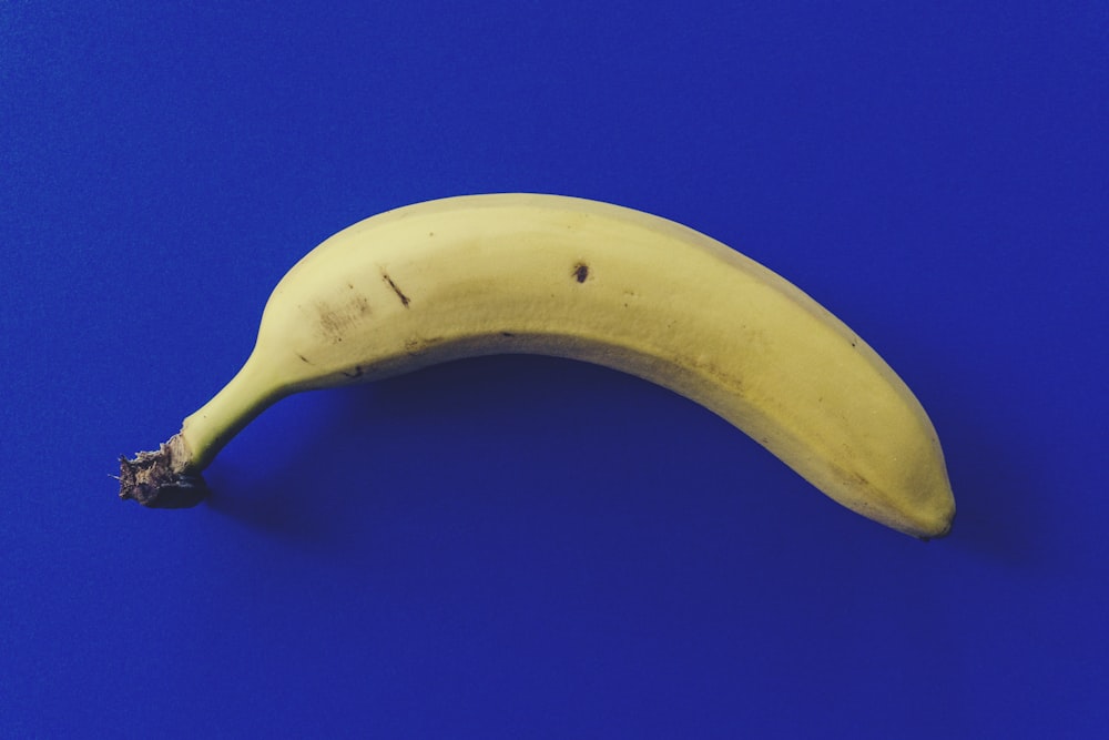 eine reife Banane, die auf einer blauen Oberfläche sitzt