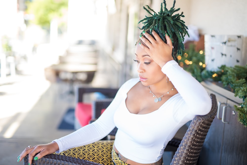 woman wearing white scoop-neck long-sleeved crop top sitting on brown armchair