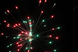 Bright red and blue fireworks exploding in symmetrical patterns against a dark sky.