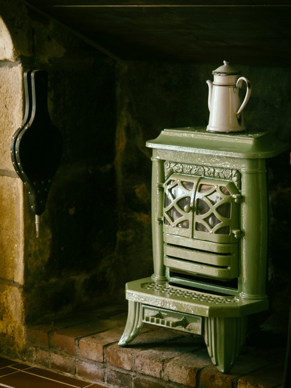 white metal teapot on green metal wood burner fireplace