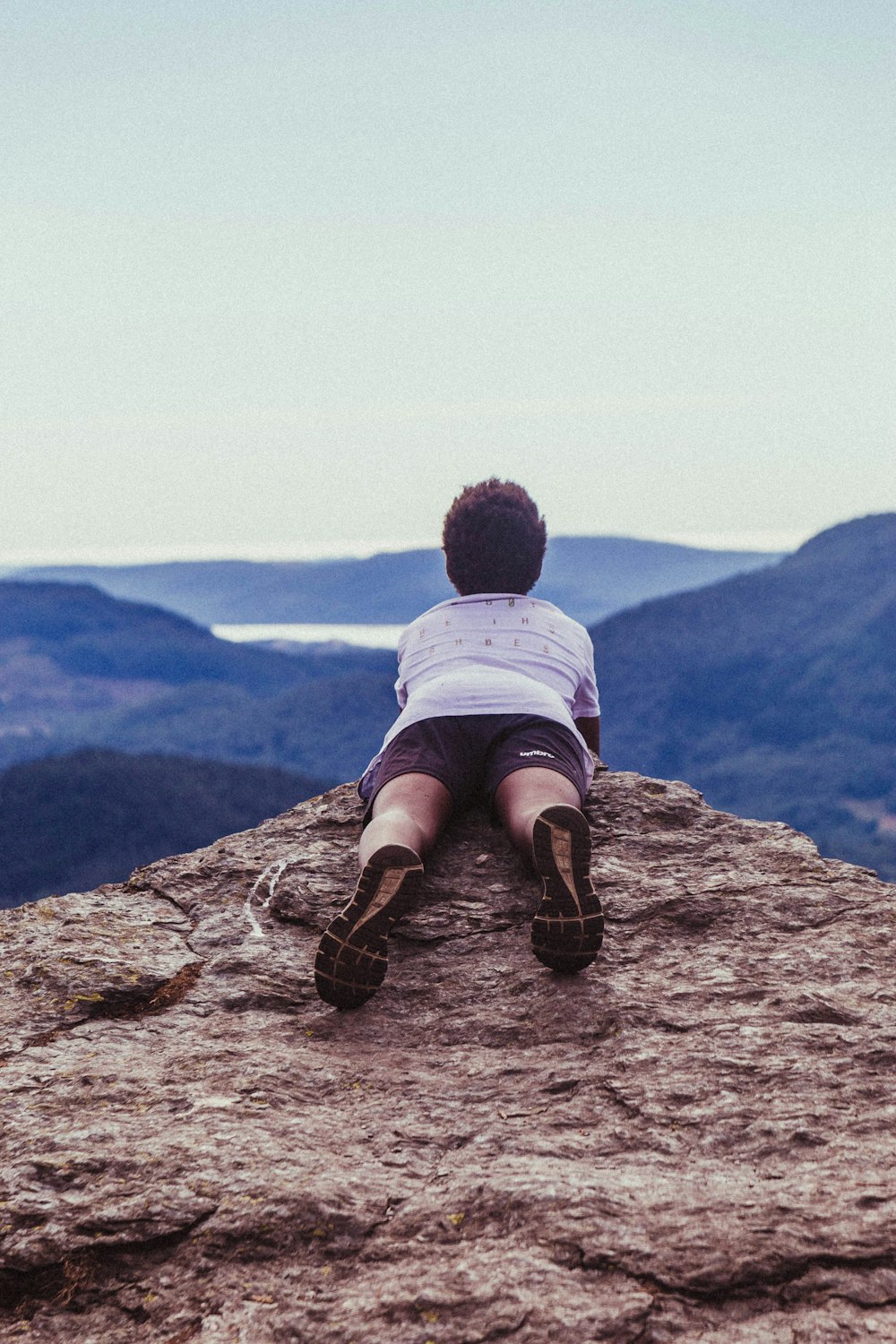 man lying on the edge of a cliff