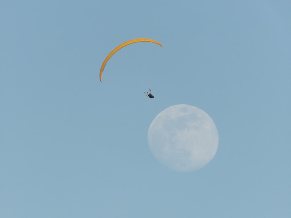 person on parachute with moon background