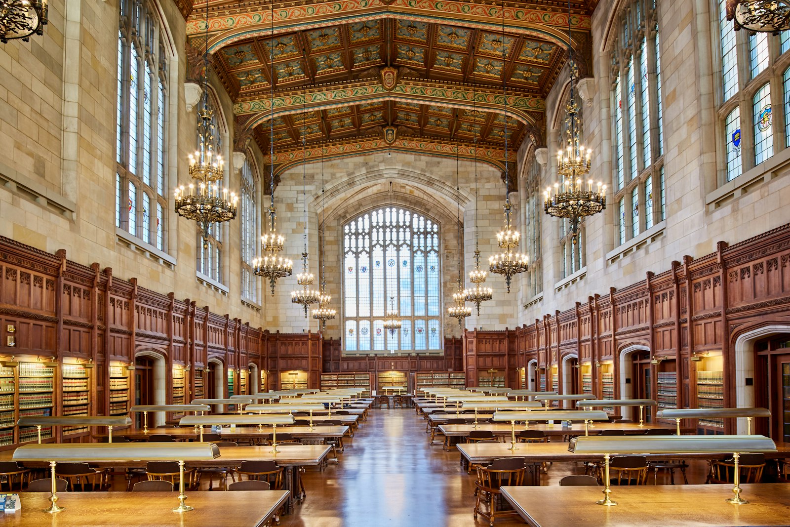 The interior of a grand reading room with long desks and chandeliers