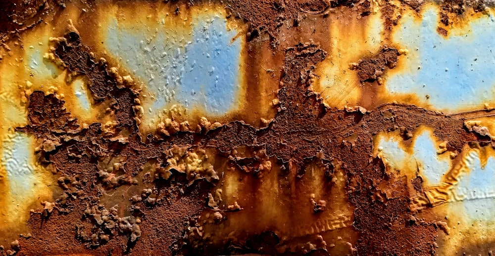 a rusted metal surface with blue and yellow paint