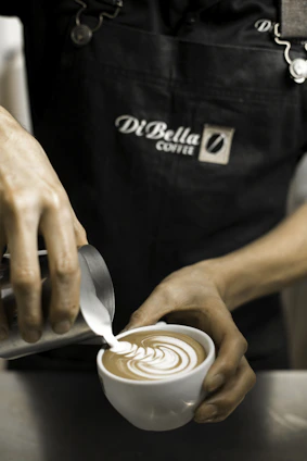 person holding cup making latte art