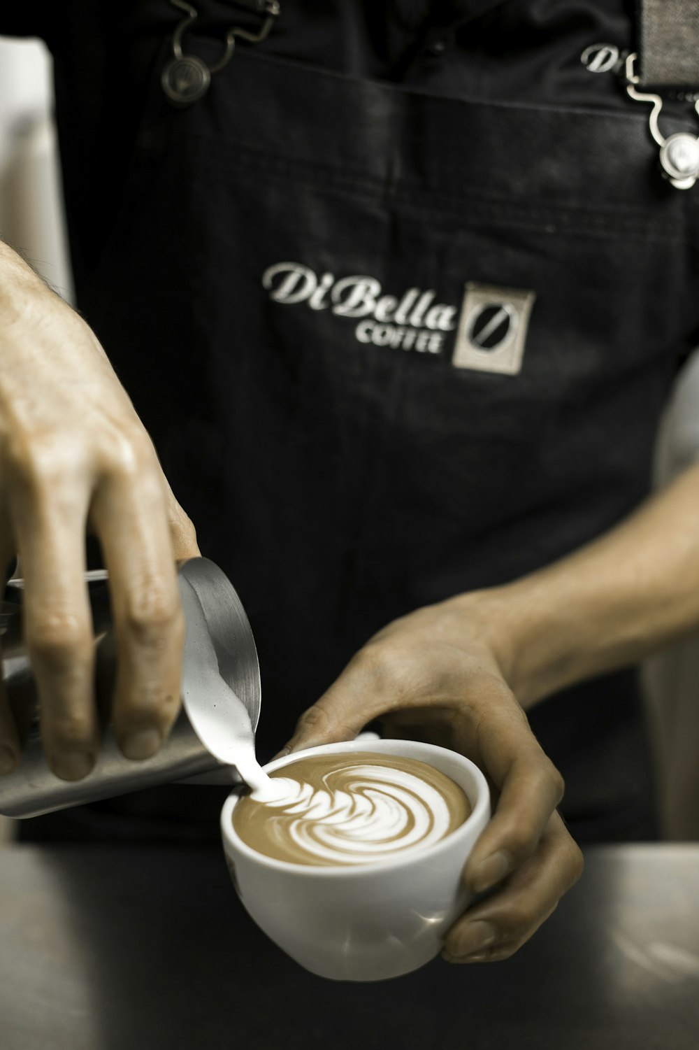 person holding cup making latte art