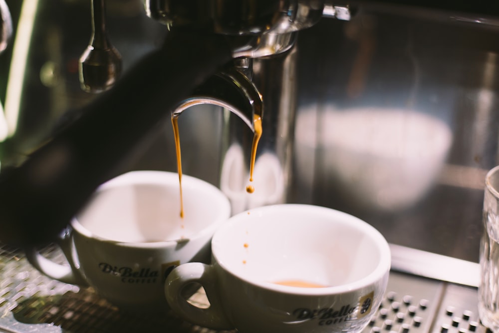 two white ceramic mugs on coffeemaker