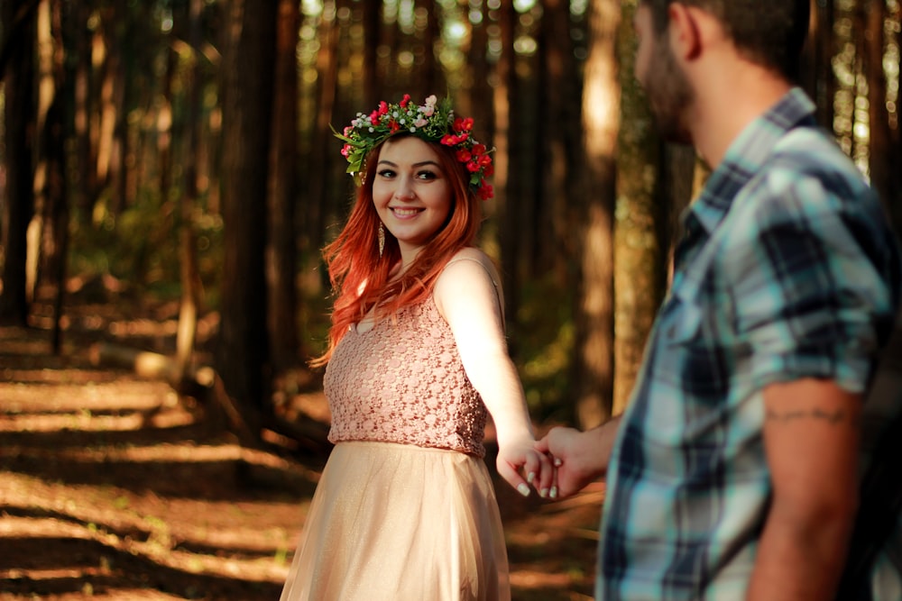 couple holding hands while standing near tree barks