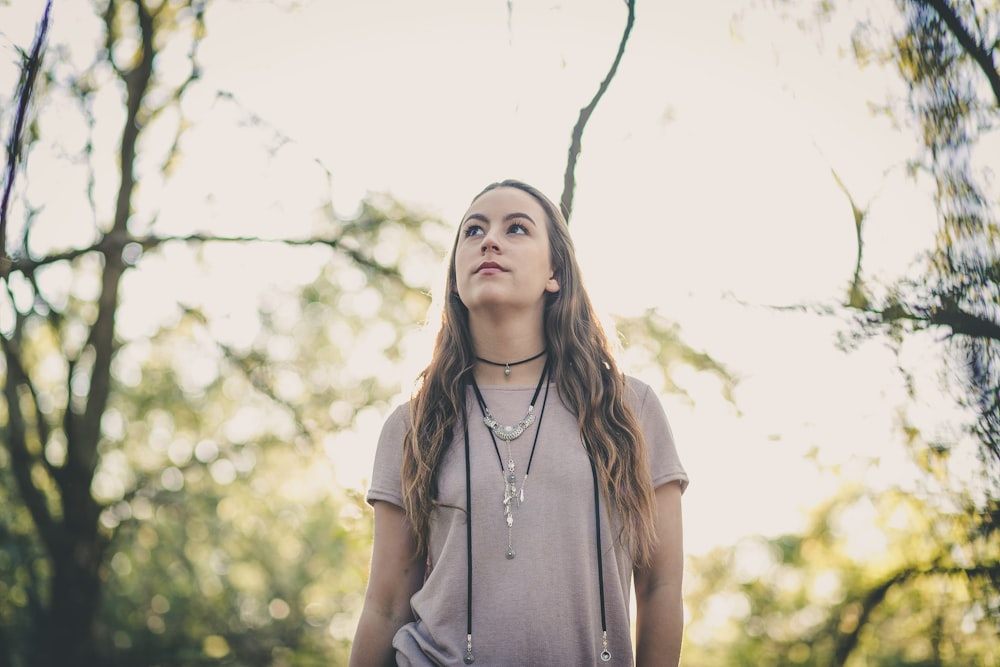 woman in gray t-shirt standing between tree branches