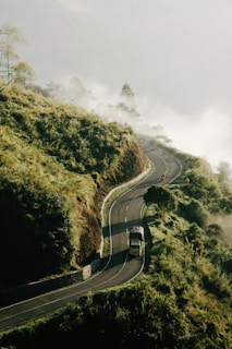 truck passing on mountain pass covered with fog