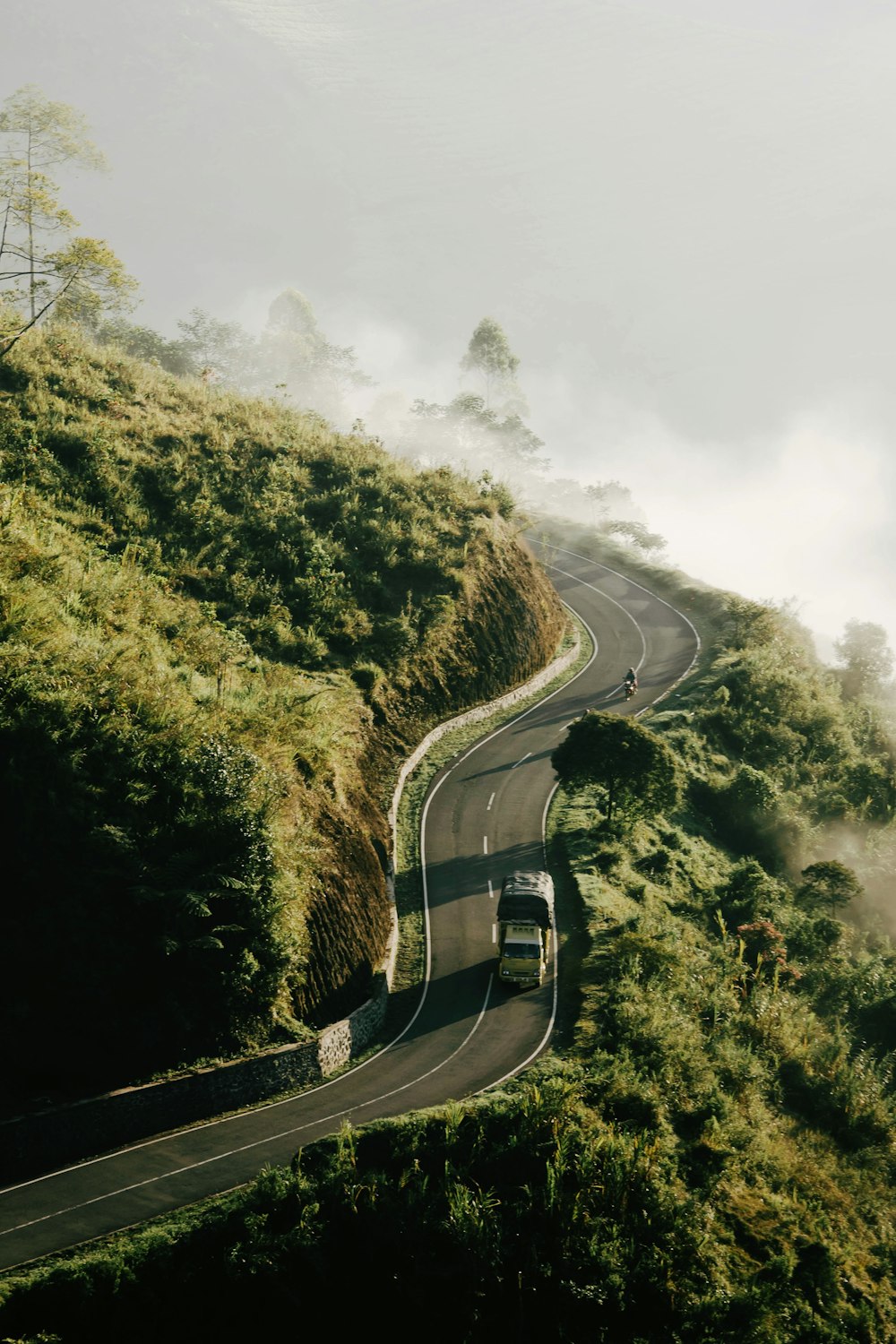 truck passing on mountain pass covered with fog