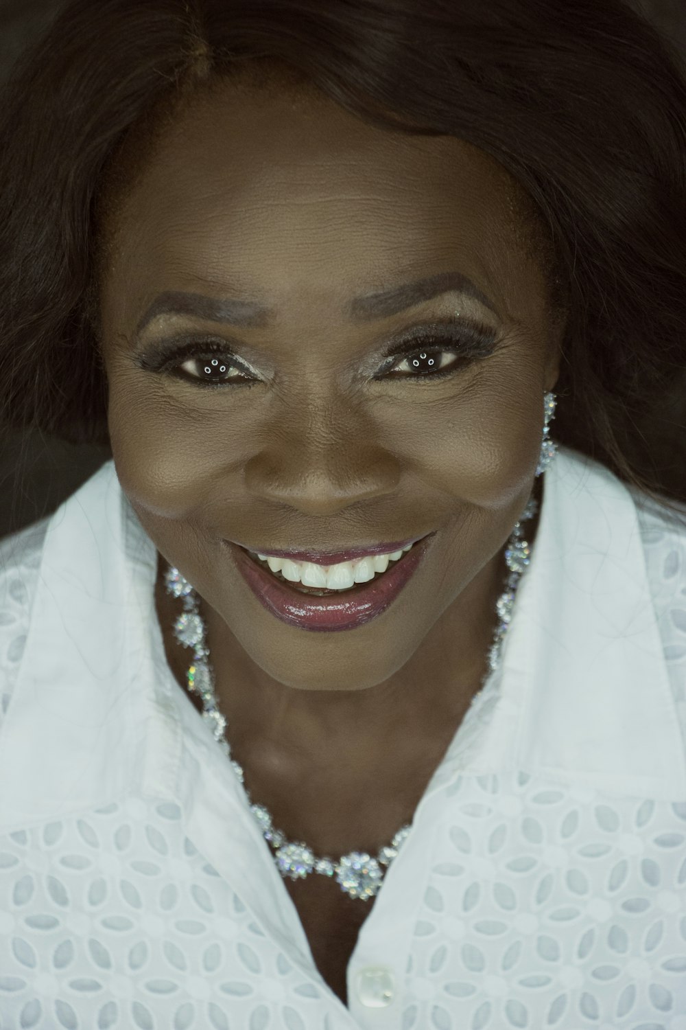 smiling woman wearing red lipstick and white top taking a selfie