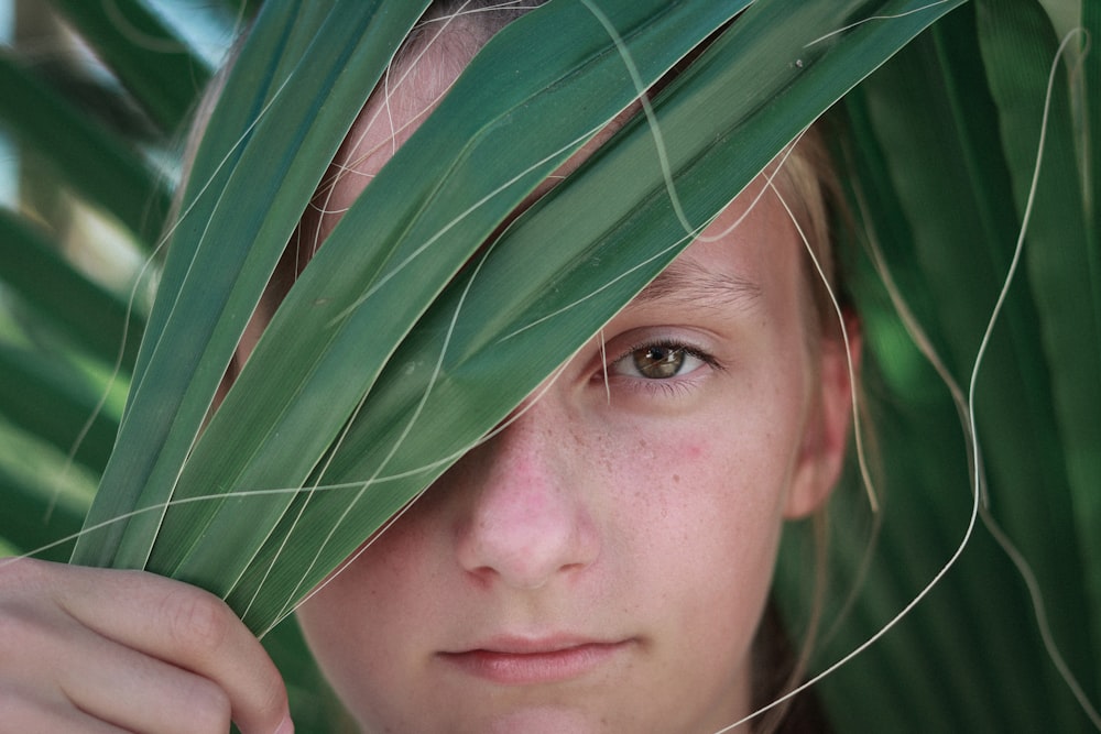 selective focus photography of woman holding leaves covering her face