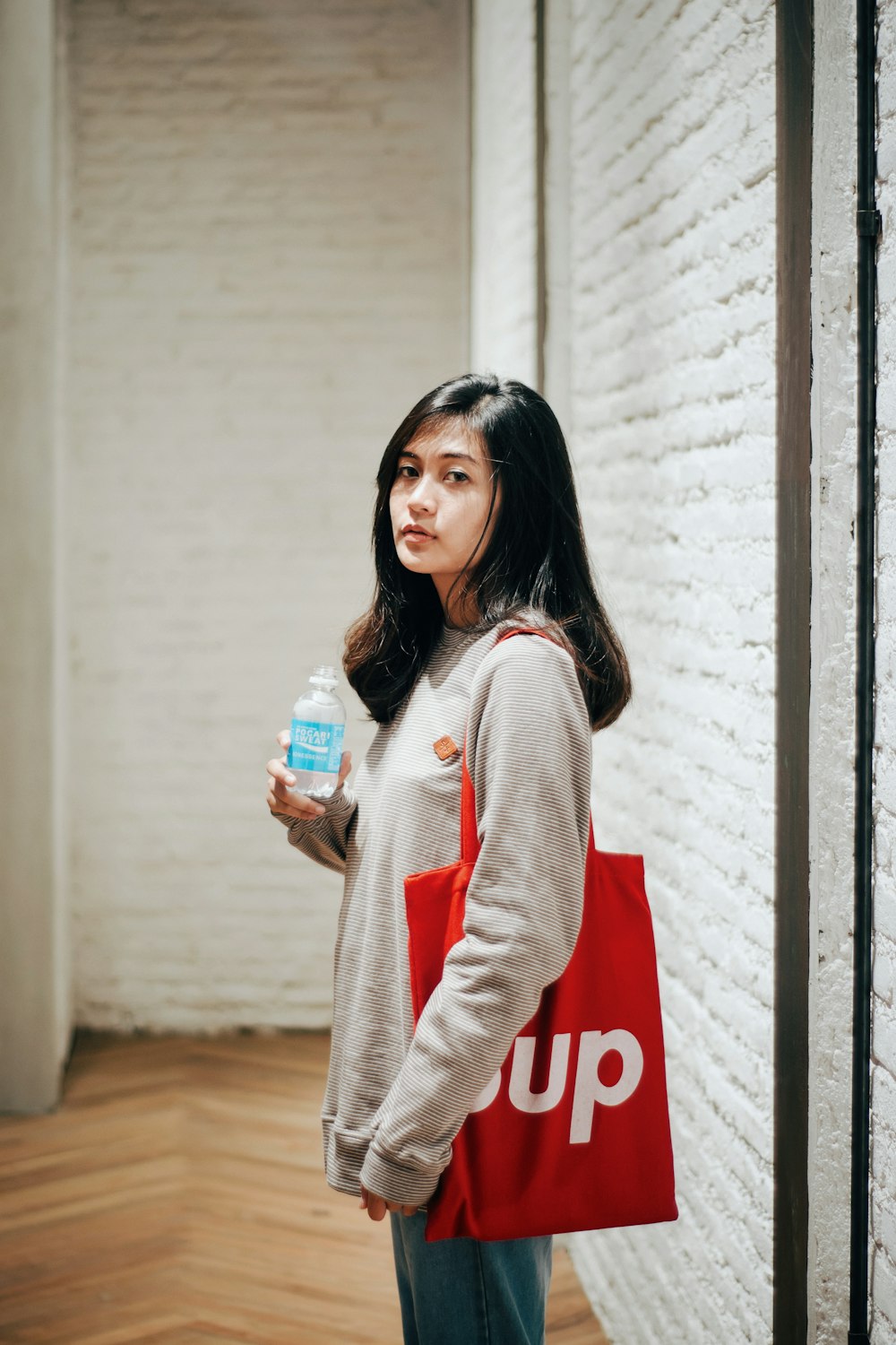 woman wearing grey shirt with Supreme tote bag