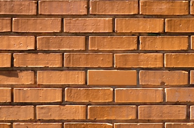Wide shot of a brick wall being built under clear daylight.
