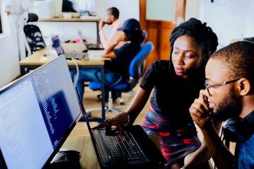 Students looking at work on a desktop computer