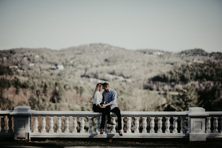 Elegant couple enjoying a quiet moment on a secluded terrace overlooking rolling hills.