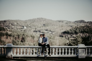A couple enjoying a calm evening on the hotel's balcony overlooking rolling hills.