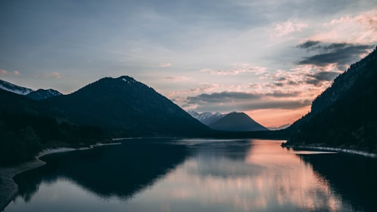 silhouette of mountain beside body of water in Sylvenstein Lake Germany