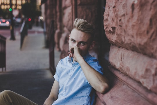 man wearing blue crew-neck sitting near the stone building in Grand Rapids United States