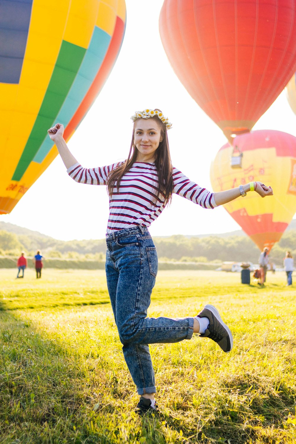 woman posing on grass field surrounded with hot air balloons
