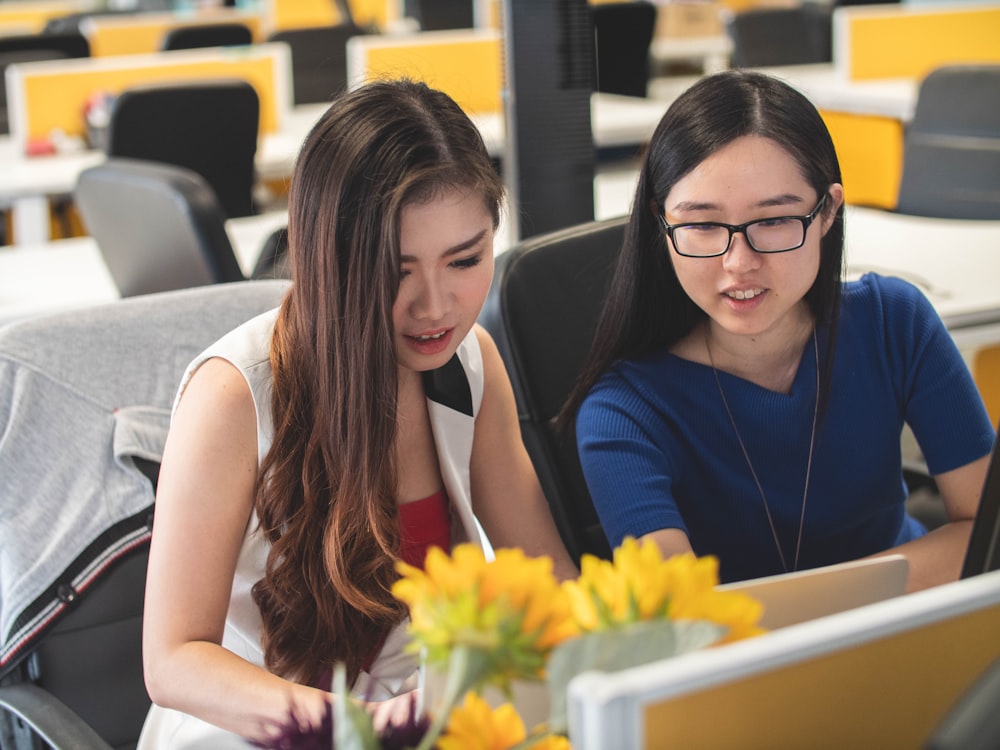 shallow focus photography of two women doing work in table