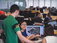 A creative team collaborating around a computer screen displaying AI-generated video ad concepts.