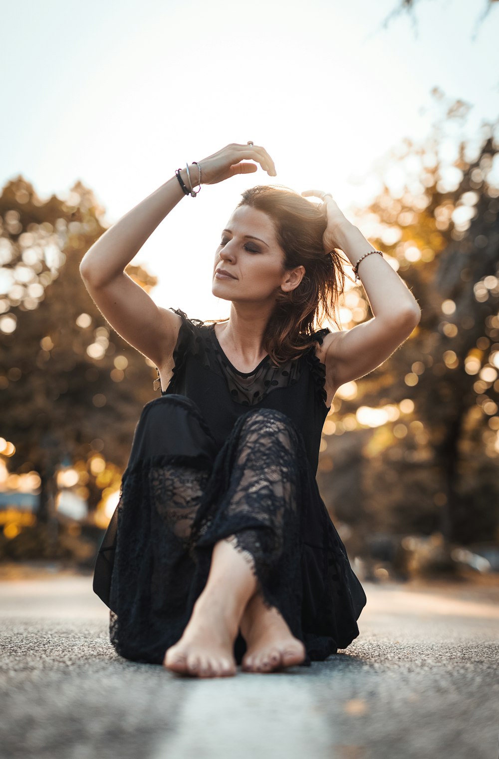 woman holding her hair while sitting near concrete road during daytime