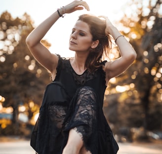 woman holding her hair while sitting near concrete road during daytime