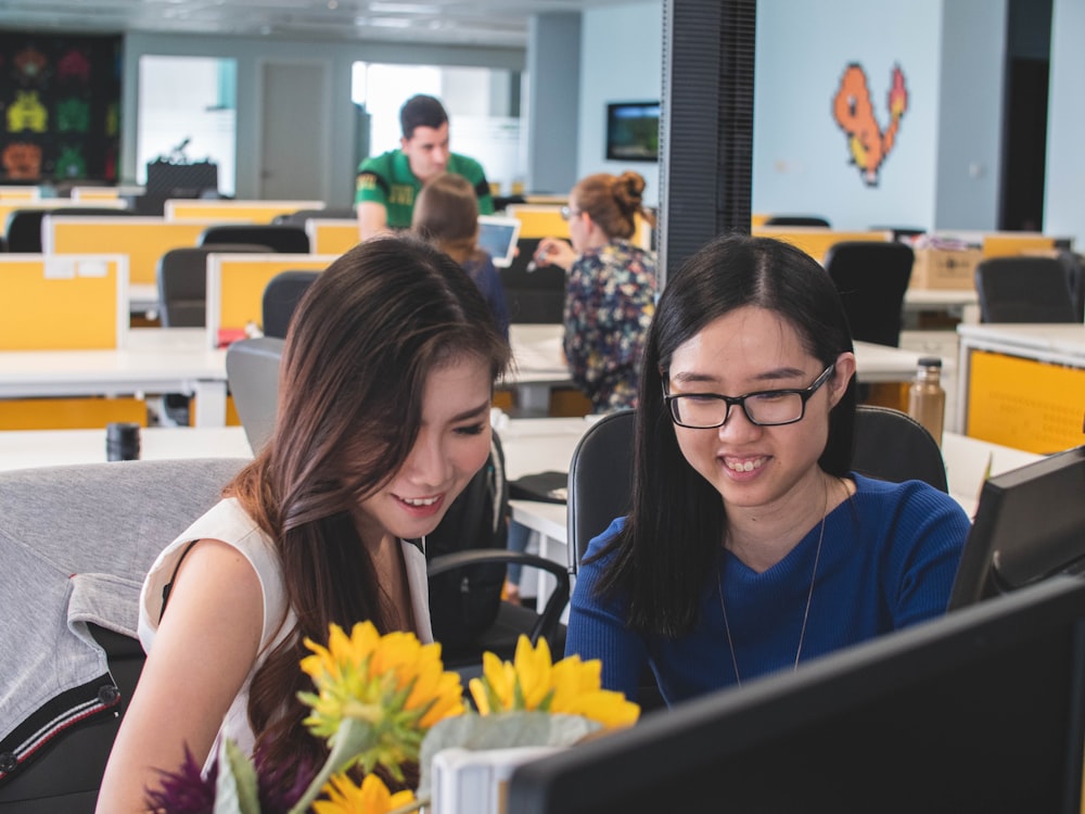 selective focus photography of two women in front of computer monitor