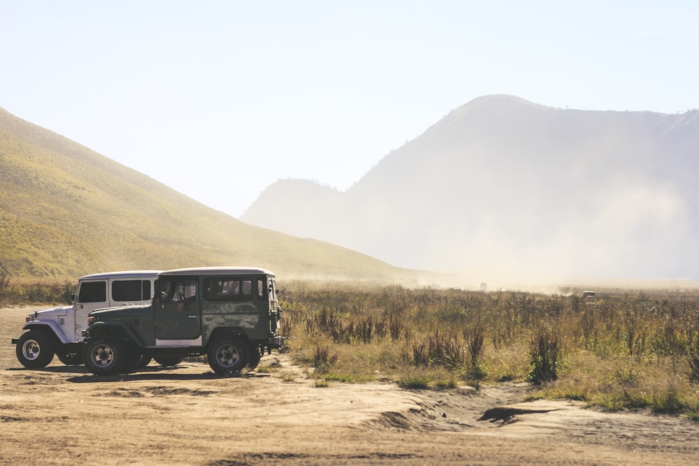 two gray and green SUV's on grass field