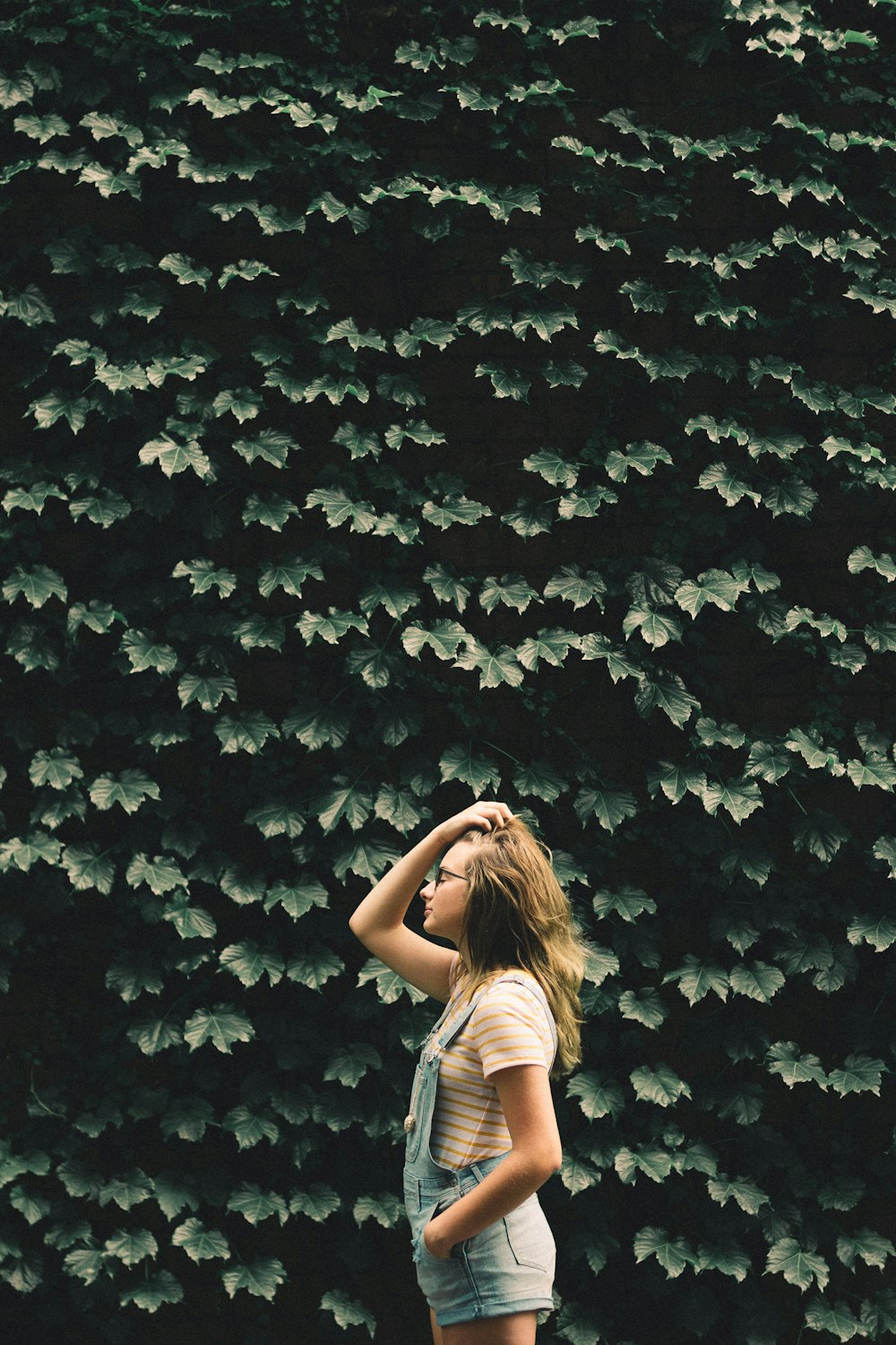 girl standing beside tree holding her hair