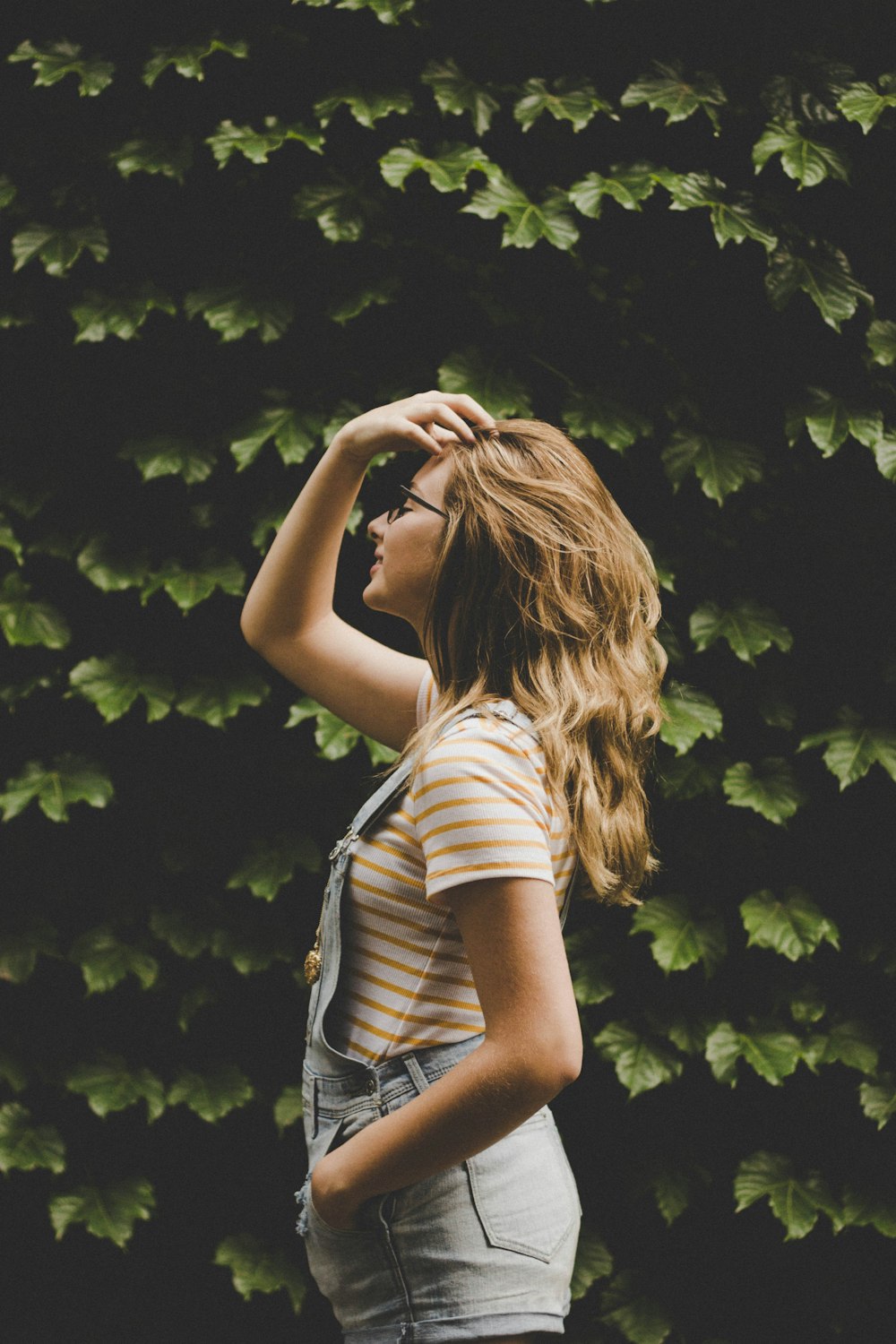 shallow focus photography of woman standing in front of plants facing sideways