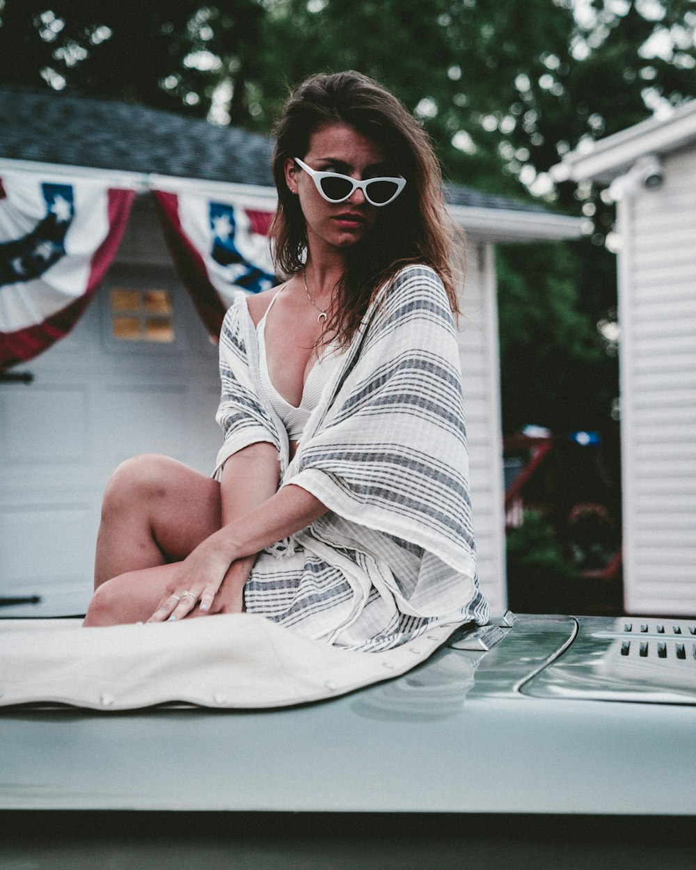 woman sitting on silver vehicle hood