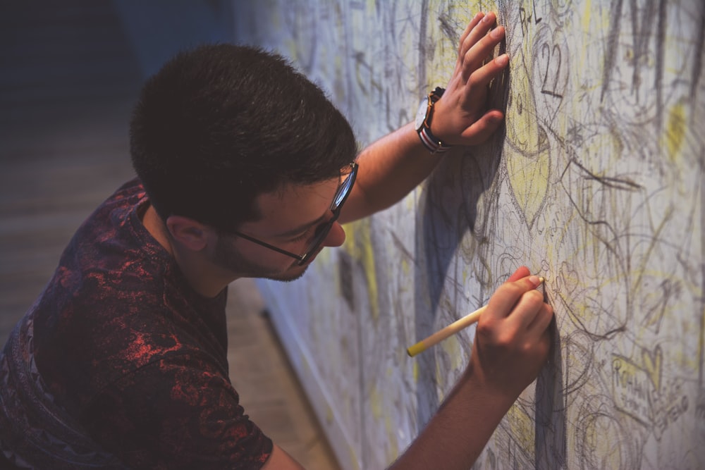 person holding pen writing on wall