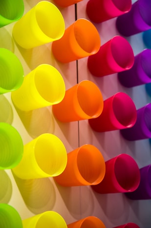 A colorful display of various cups arranged on wooden shelves, highlighting different styles and textures.
