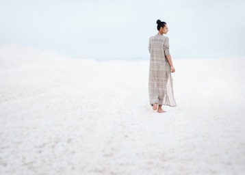 negative space for photo composition,how to photograph white sun; woman in gray dress walking on sand