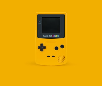 white and black Nintendo Game Boy Color on yellow surface