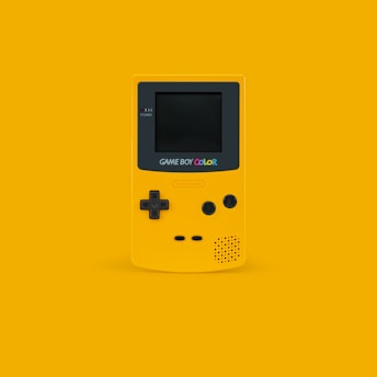 white and black Nintendo Game Boy Color on yellow surface