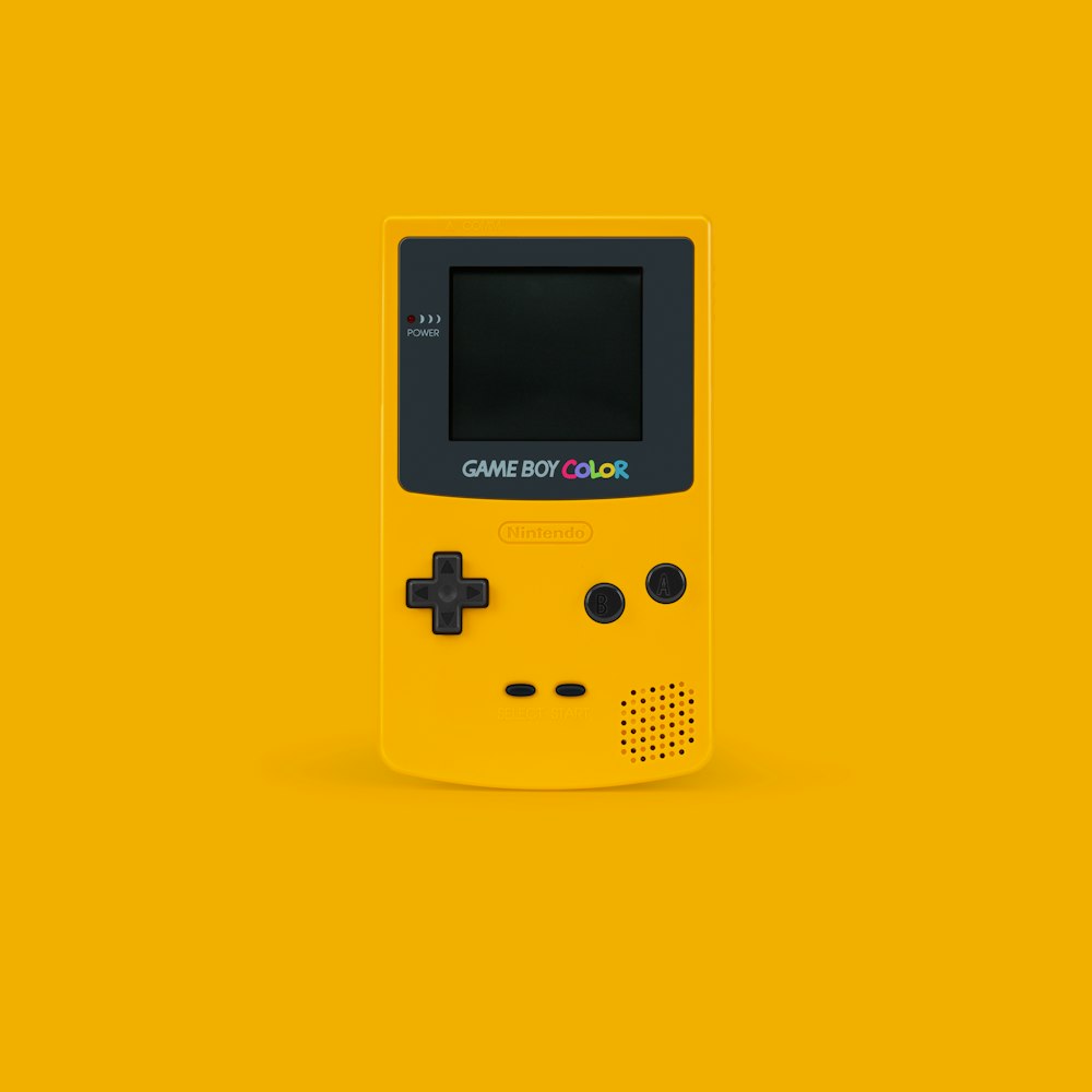 white and black Nintendo Game Boy Color on yellow surface