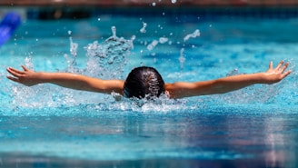 Close-up of powerful swimming strokes creating ripples in a sunlit pool, symbolizing each swimmer’s impact.