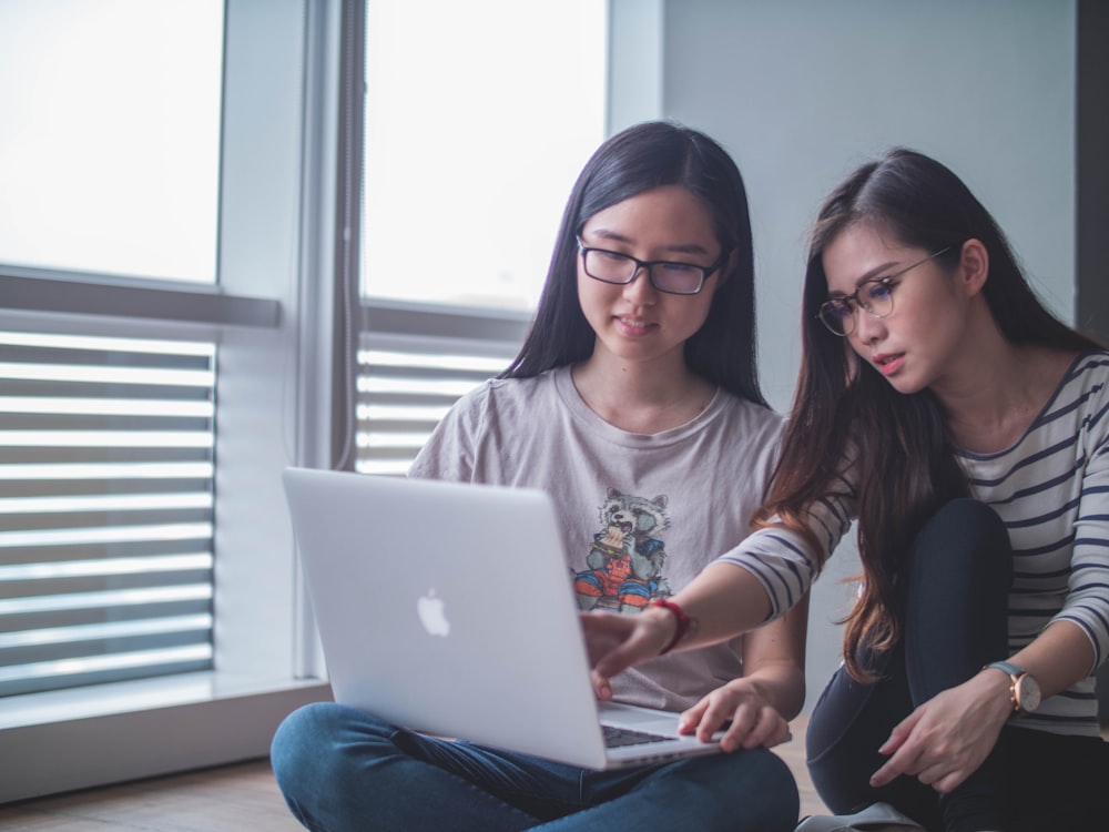 two women discussing each other while looking on laptop