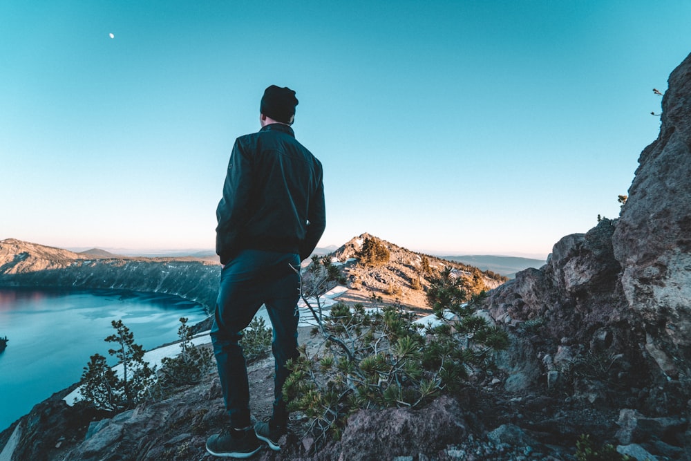 man standing on hill near bodies of water during daytime