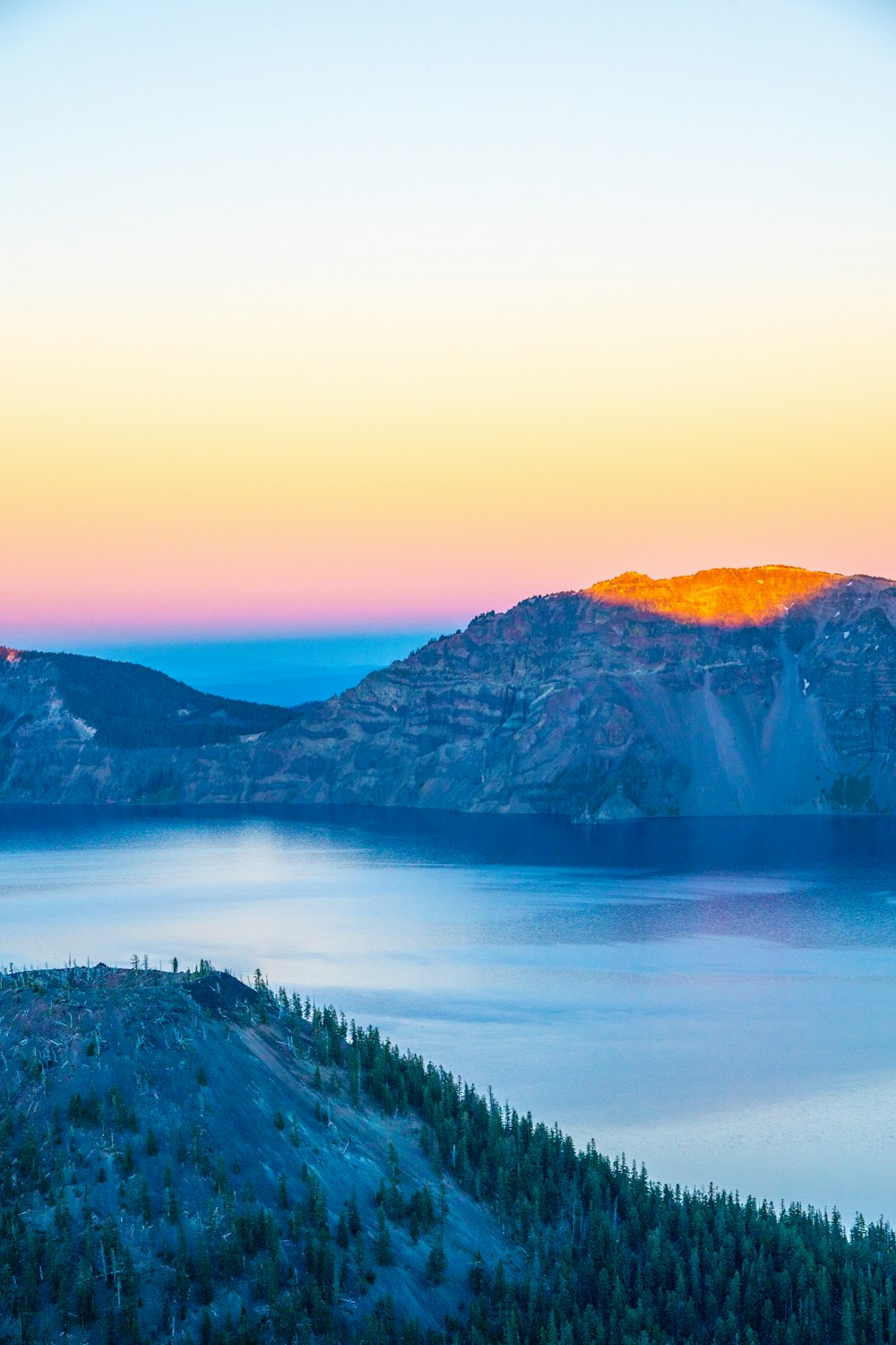 Montaña rocosa marrón rodeada de lago tomada durante el día