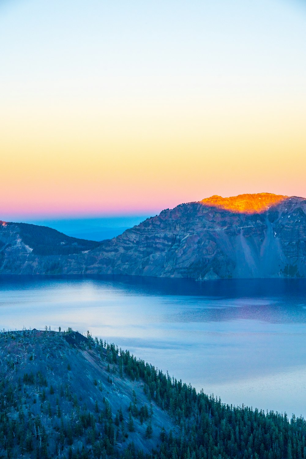 brown rocky mountain surrounded by lake taken at daytime