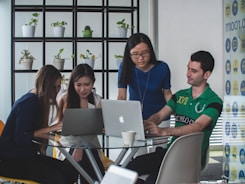 Group of professionals brainstorming around a table with digital devices and coffee cups.