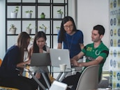 A group of professionals collaborating around a table with laptops and technical equipment.